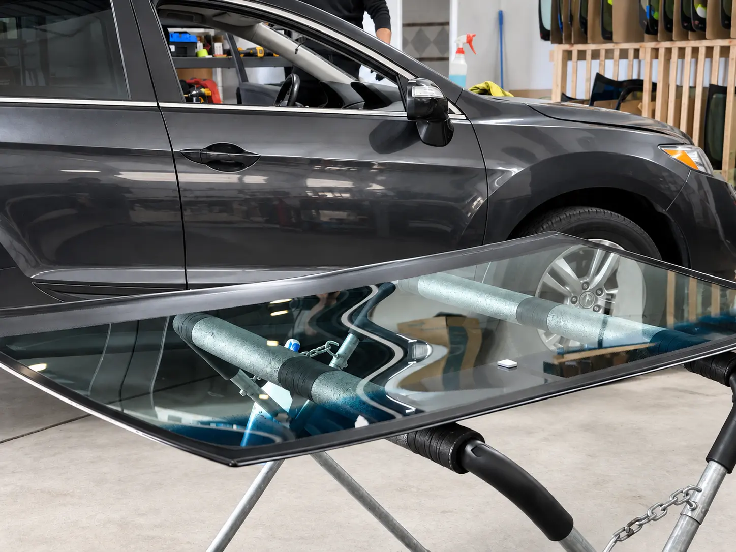 Gray Acura beside replacement windshields in the QuickGlass workshop